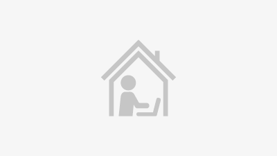 A small icon of a person working behind a laptop in a house resembling the possibility of working at home.
