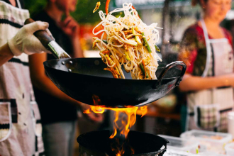 A man using a wok to cook up a stir fry
