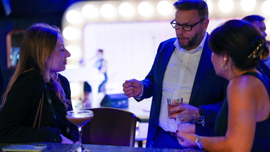 Campfire Talk attendees hanging out at the bar of a private lounge with live entertainment