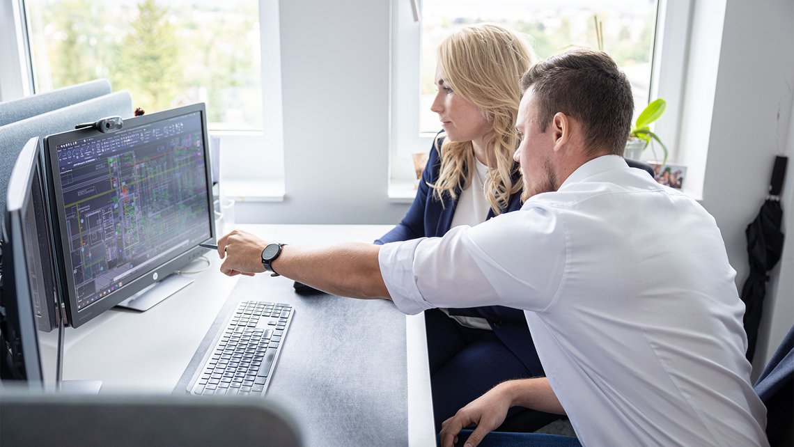 A man shows a women something on an laptop screen