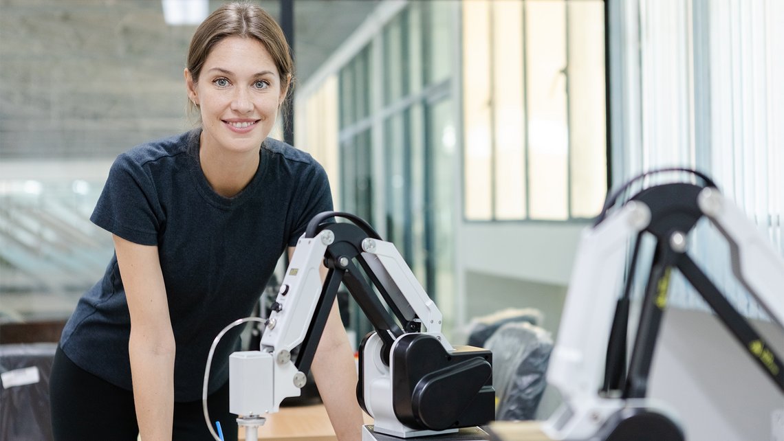 A woman smiling at the camera while operating multiple pickrobots