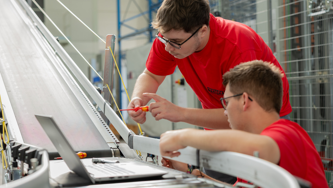 Two apprentice students working on a TGW Logistics conveyor