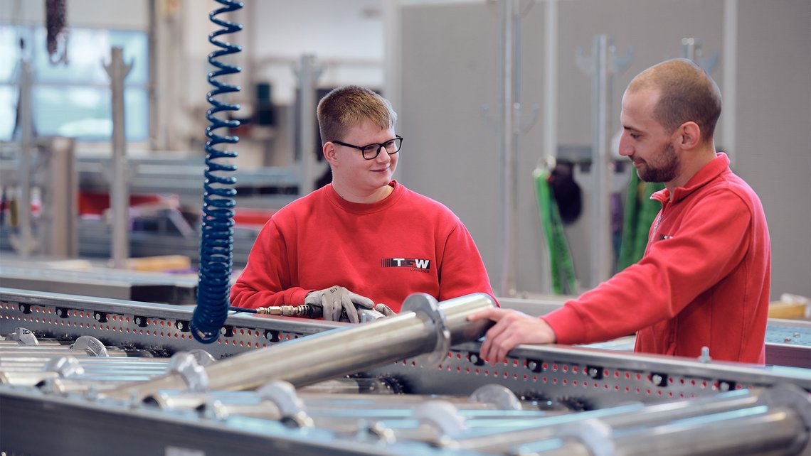 A new apprentice at TGW Logistics being taught all the ins and outs of the conveyor belt systems by a senior employee