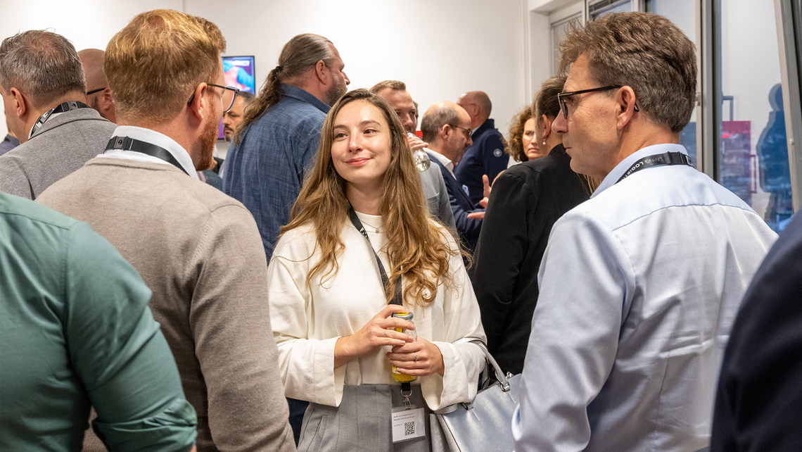 Group of people and TGW Logistics employees networking at an event