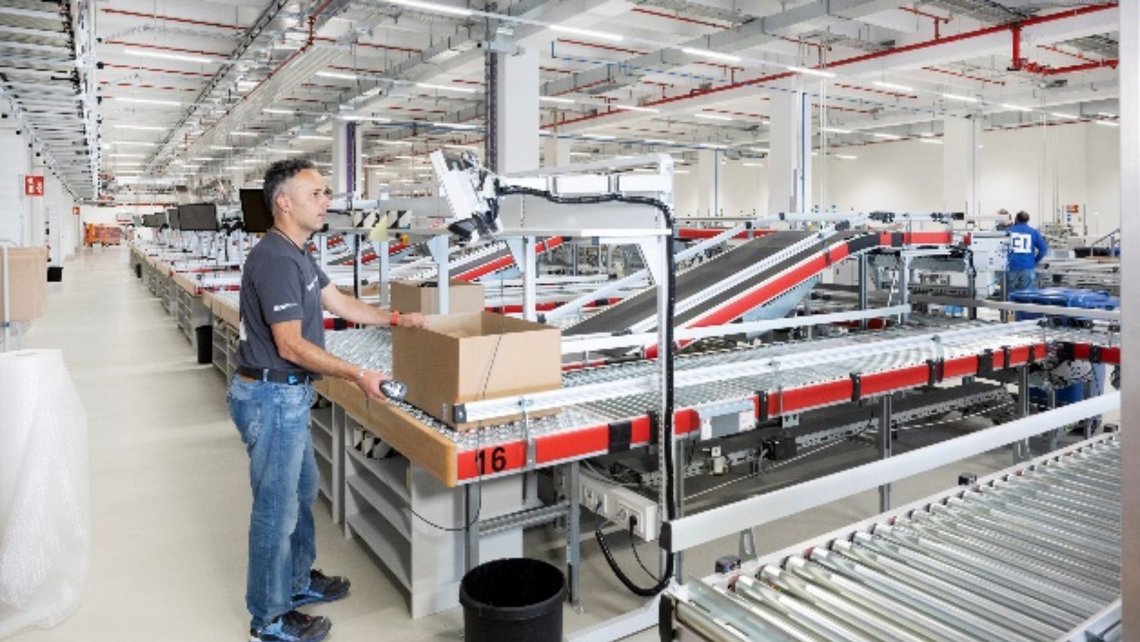 A worker at a warehouse picking station