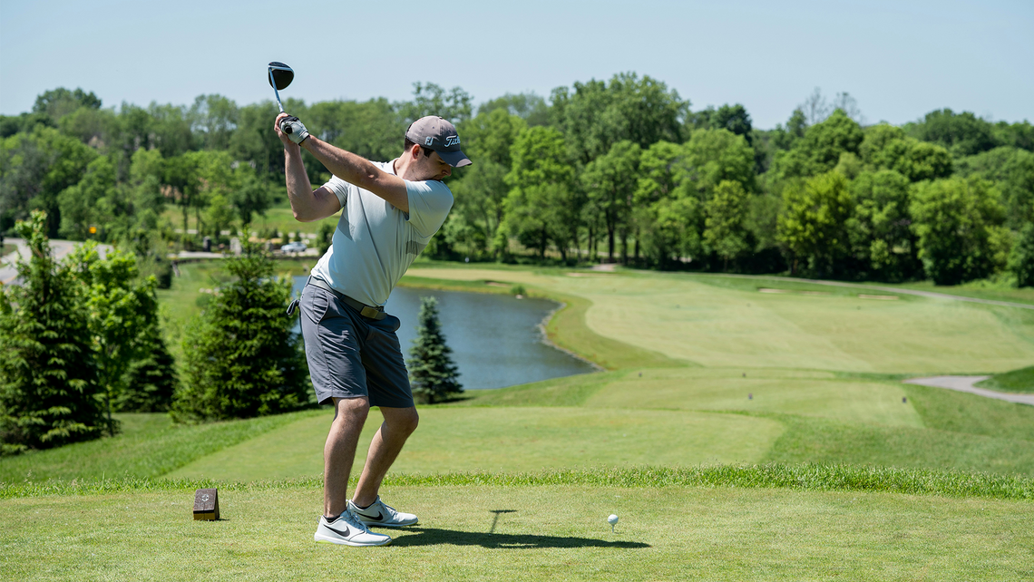 Man in a white shirt and shorts golfing