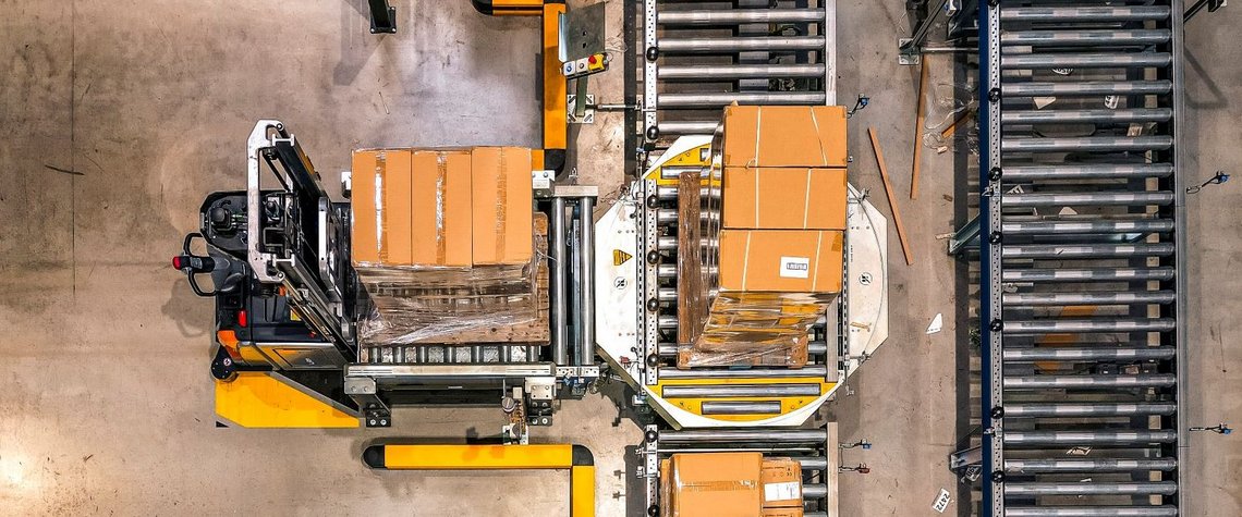 Overview of an automated warehouse where cartons are being placed from forklifts on conveyor belts.