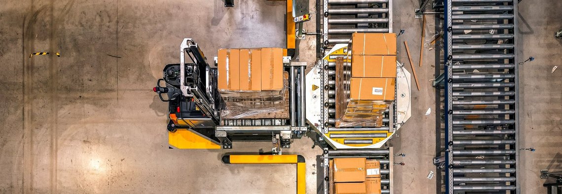 Overview of an automated warehouse where cartons are being placed from forklifts on conveyor belts.