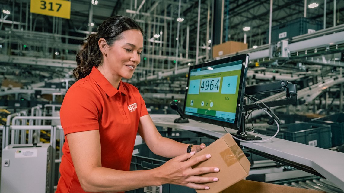 Worker wearing a red polo picking at a TGW Logistics PickCenter One