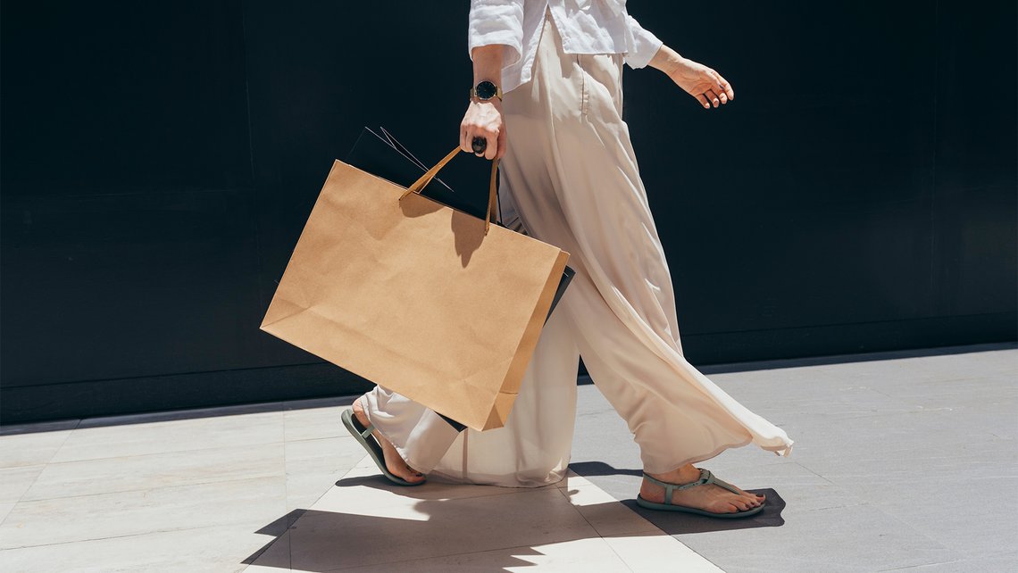 A woman walking down the street with a big shopping bag