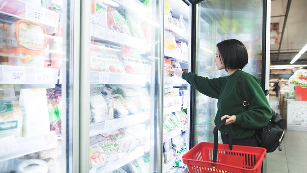 A woman grabbing something from the refrigerated aisles in a supermarket