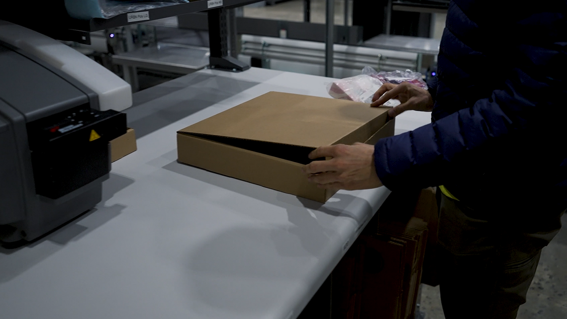 Warehouse worker putting picked items for an URBN order into a box