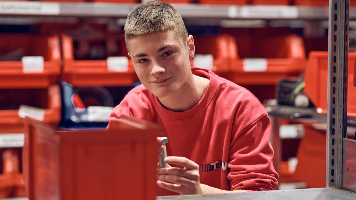 A TGW Logistics apprentice smiling at the camera while working in the training center