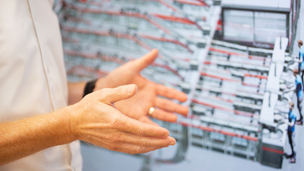 TGW Logistics' employee's hands in front of a screen, presenting the FlashPick solution for flexible logistics