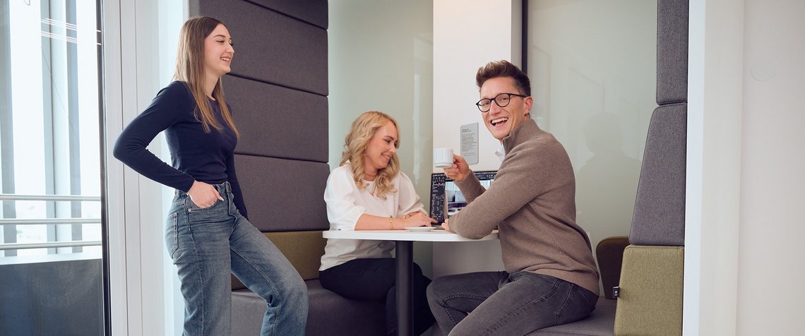 Three TGW Logistics employees enjoying a coffee break in the modern canteen benches