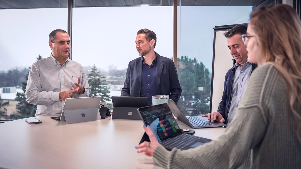 Group of TGW Logistics' employees discussing topics around a standing table