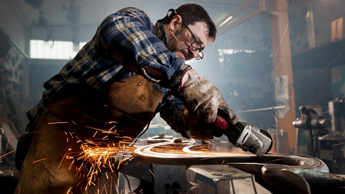 A handy man working with power tools in his shed with little sparks coming from it