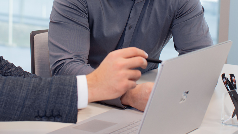 Two men looking at a touchscreen laptop, discussing warehouse automation solutions