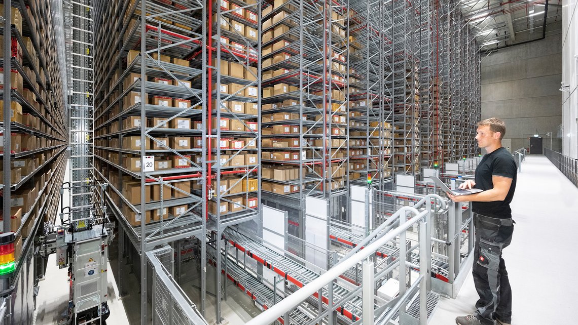 A TGW Logistics employee standing and looking at massive rackings inside a warehouse