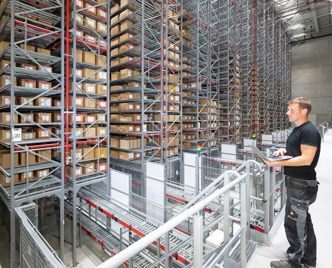 A TGW Logistics employee standing and looking at massive rackings inside a warehouse